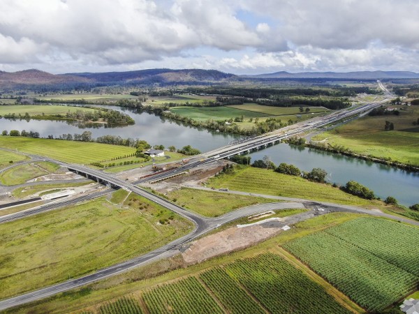 Aerial view looking over cane fields at bridge over highway and another bridge over water
