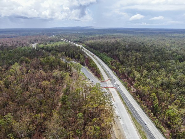Aerial image of highway with burnt trees on either side 